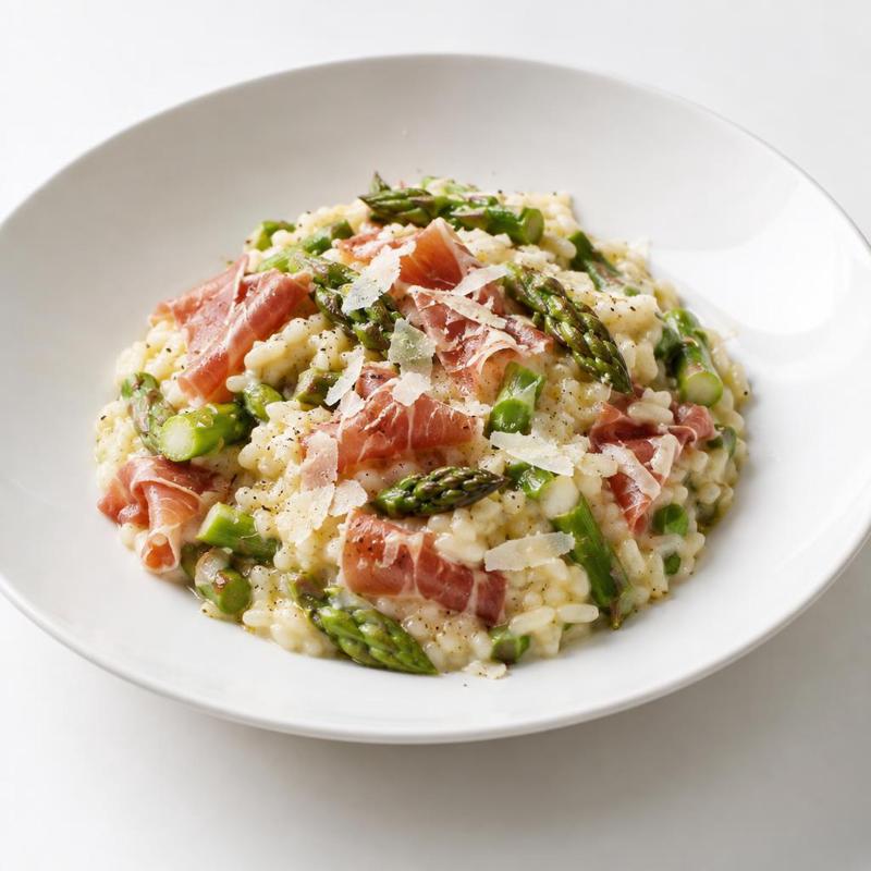 Kremowe risotto z zielonymi szparagami i prosciutto, wykończone parmezanem